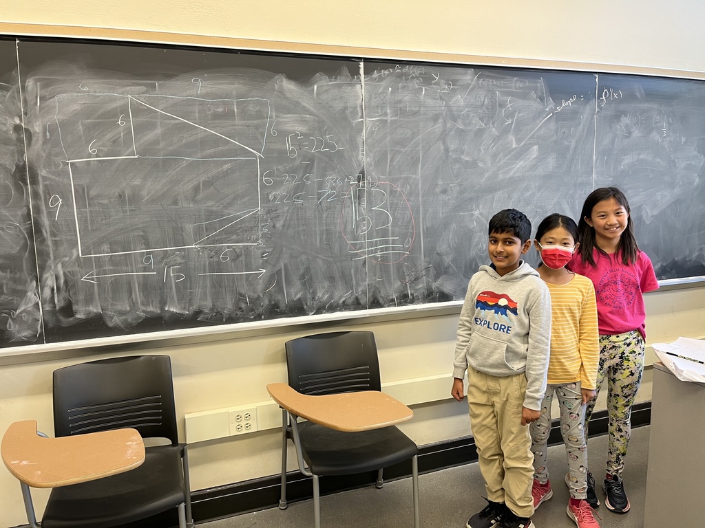 Students stand in front of a blackboard with math written on it